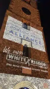 St Albans clocktower lit up with the Domestic Abuse Alliance logo and White Ribbon logo for White Ribbon Day 2021